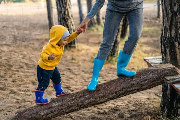 mother helping child go up on a log